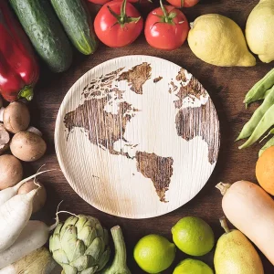 frutta e verdura di vario genere attorno ad un piatto di legno con illustrato un mondo