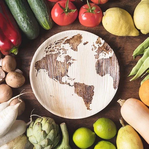 frutta e verdura di vario genere attorno ad un piatto di legno con illustrato un mondo