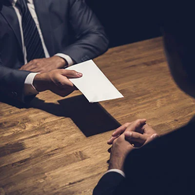 Mani di due persone che tengono un foglio e partecipano al corso Anticorruzione e trasparenza