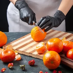 cuoco con guanti che taglia la frutta con attenzione