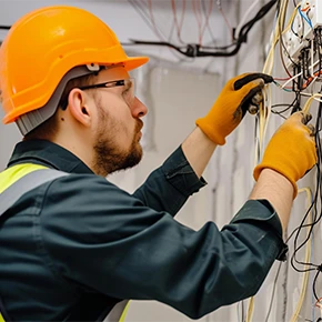 Elettricista con guanti e caschetto lavora in sicurezza con i cavi