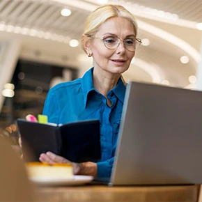 Donna in ufficio che guarda il computer e prende appunti